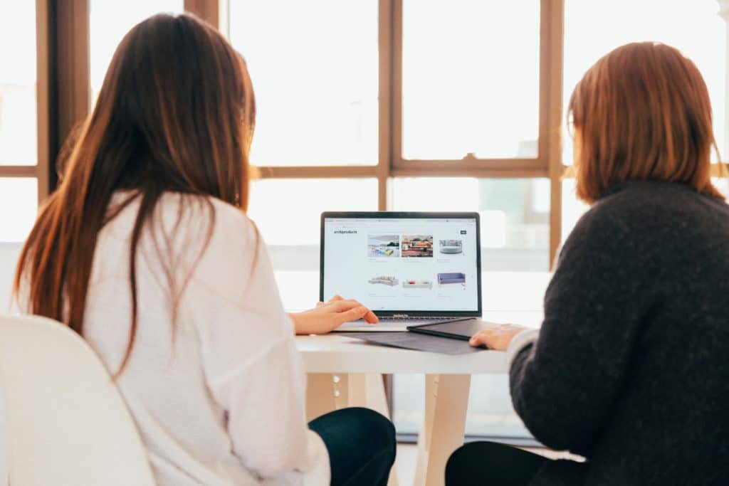 Two people reviewing a website on a laptop