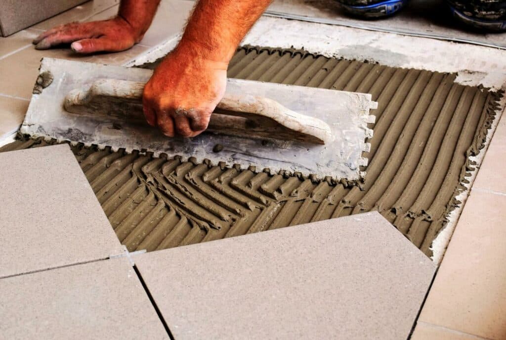 A man creates grooves to lay down concrete tiles.