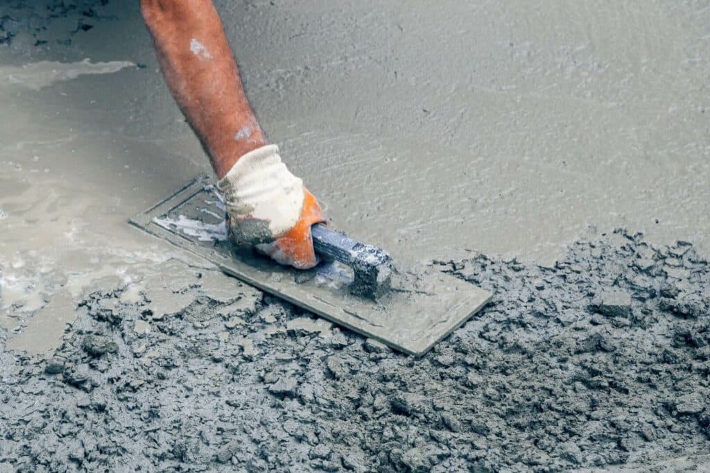 A contractor smooths concrete with a hand tool.