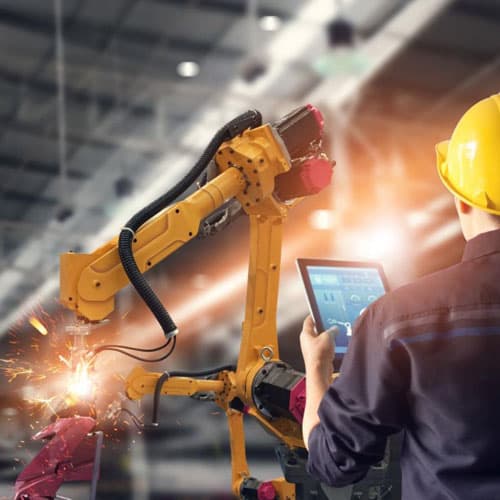 A person in yellow hard hat looking at content marketing analytics with robot arms in the background.