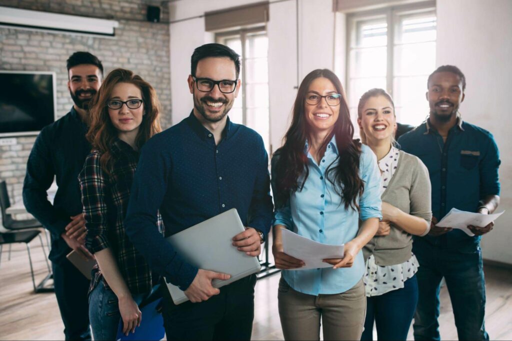 A group of six team members standing in a row and smiling.
