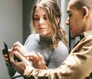 social media marketing image showing a marketing professional showing images on his smartphone to his colleague