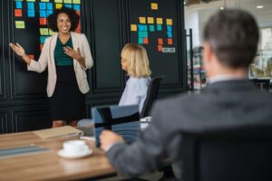 digital marketing consultant image showing a standing woman enthusiastically discussing a presentation to a group of executives