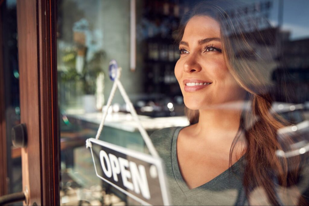 A woman opening a franchise location and looking out a window.